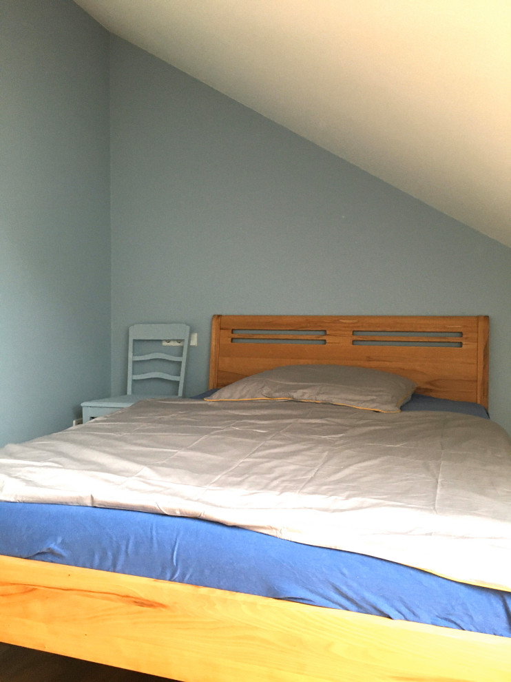 Modelo de dormitorio principal escandinavo pequeño con paredes azules, suelo de madera en tonos medios y suelo marrón