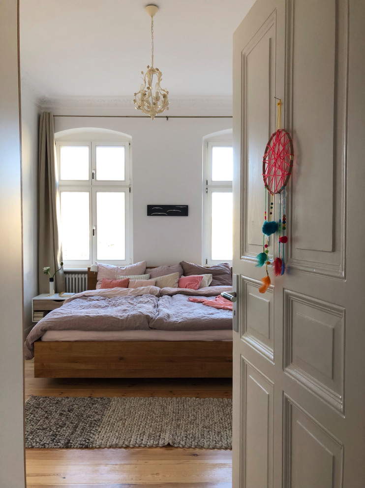 Cette image montre une petite chambre parentale design avec un mur blanc, parquet clair et un sol marron.