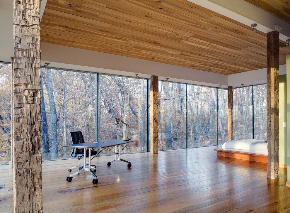 Modelo de dormitorio minimalista con suelo de madera en tonos medios y con escritorio