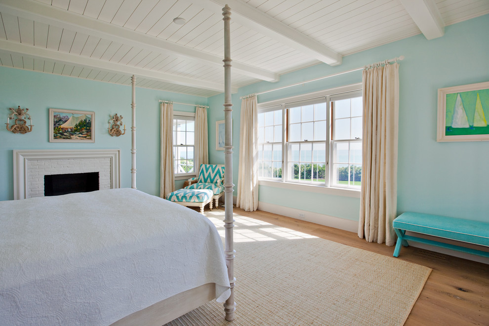 Large beach style master medium tone wood floor bedroom photo in Boston with blue walls, a standard fireplace and a brick fireplace