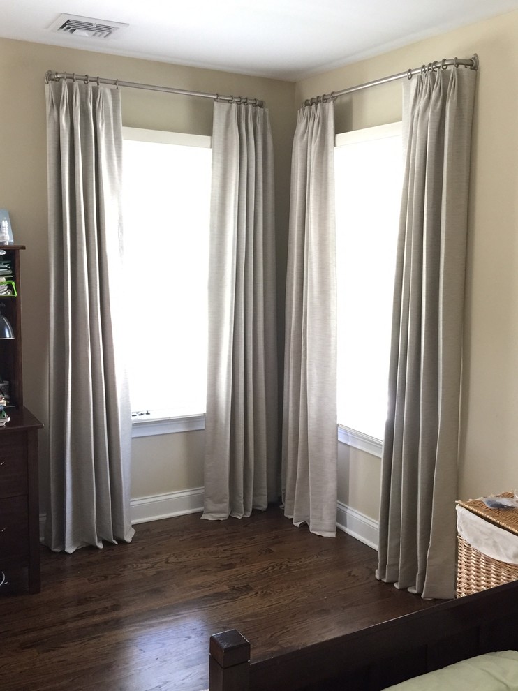 Medium sized modern bedroom in New York with beige walls and dark hardwood flooring.