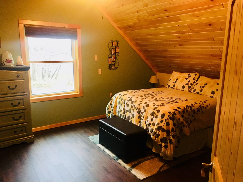 Modelo de dormitorio principal rural con paredes verdes, suelo laminado y suelo marrón