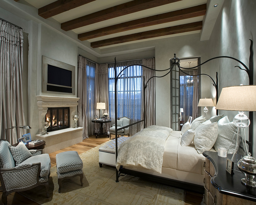 Пример оригинального дизайна: спальня с серыми стенами, паркетным полом среднего тона и стандартным камином