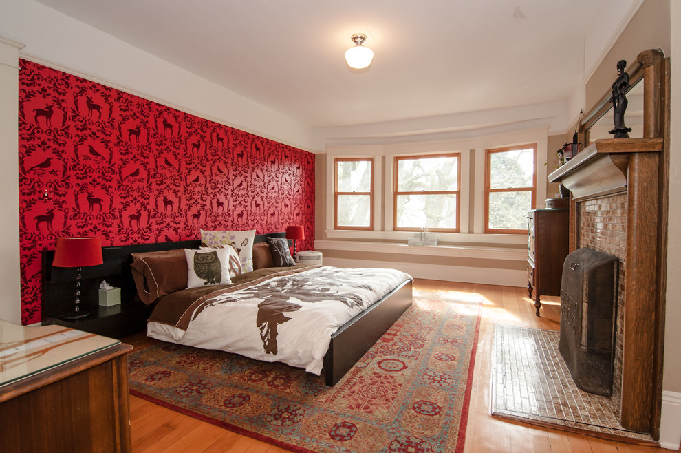 Foto de dormitorio bohemio con paredes rojas, suelo de madera en tonos medios y todas las chimeneas