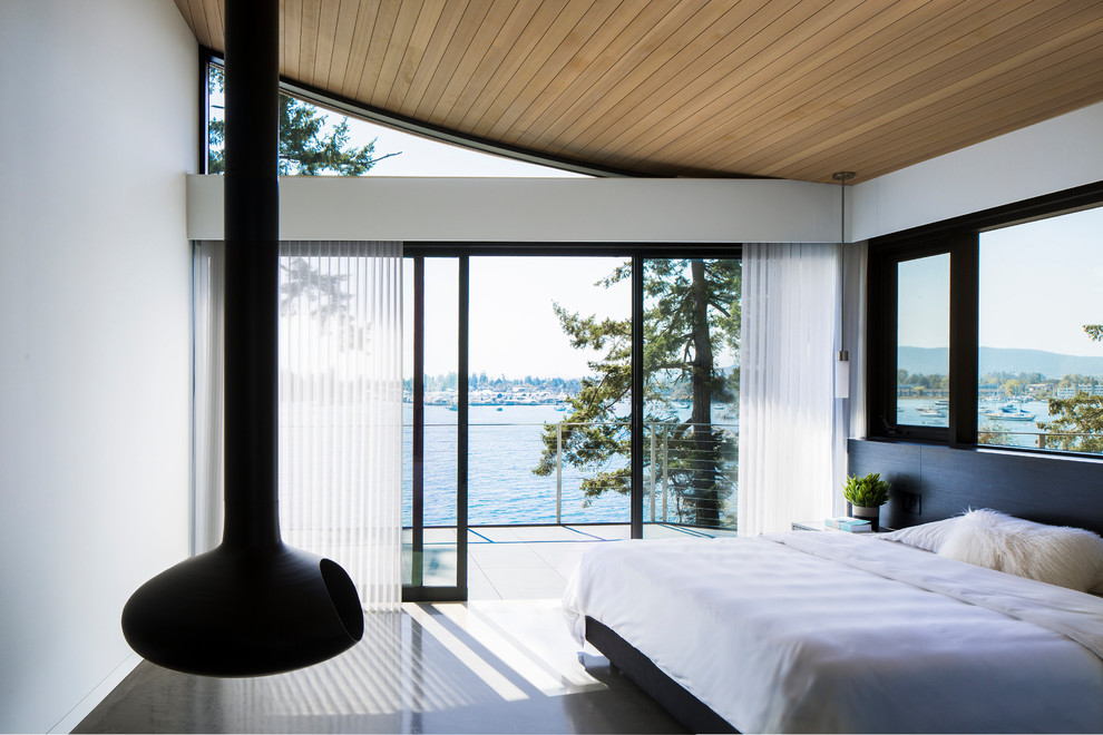 Идея дизайна: хозяйская спальня среднего размера в современном стиле с белыми стенами, бетонным полом, подвесным камином и серым полом