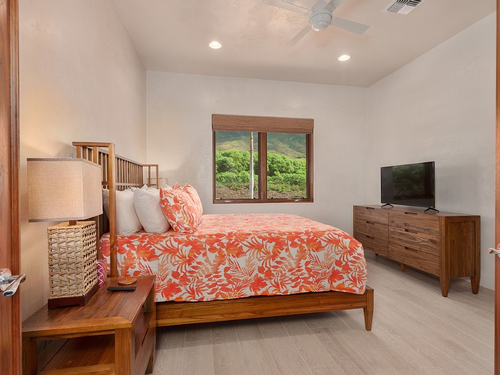 Mittelgroßes Hauptschlafzimmer ohne Kamin mit weißer Wandfarbe, hellem Holzboden und beigem Boden in Hawaii