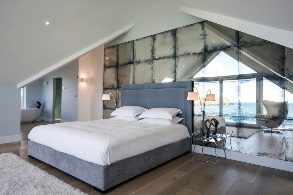 Modern inredning av ett stort sovrum, med grå väggar, mörkt trägolv och brunt golv