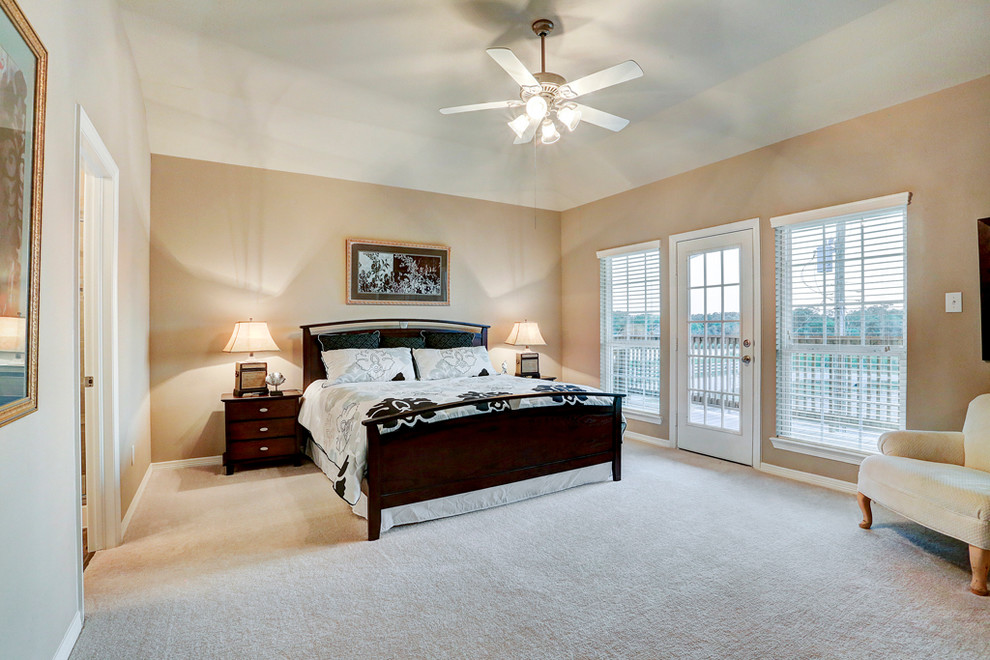 This is an example of a large classic master bedroom in Houston with beige walls, carpet and no fireplace.