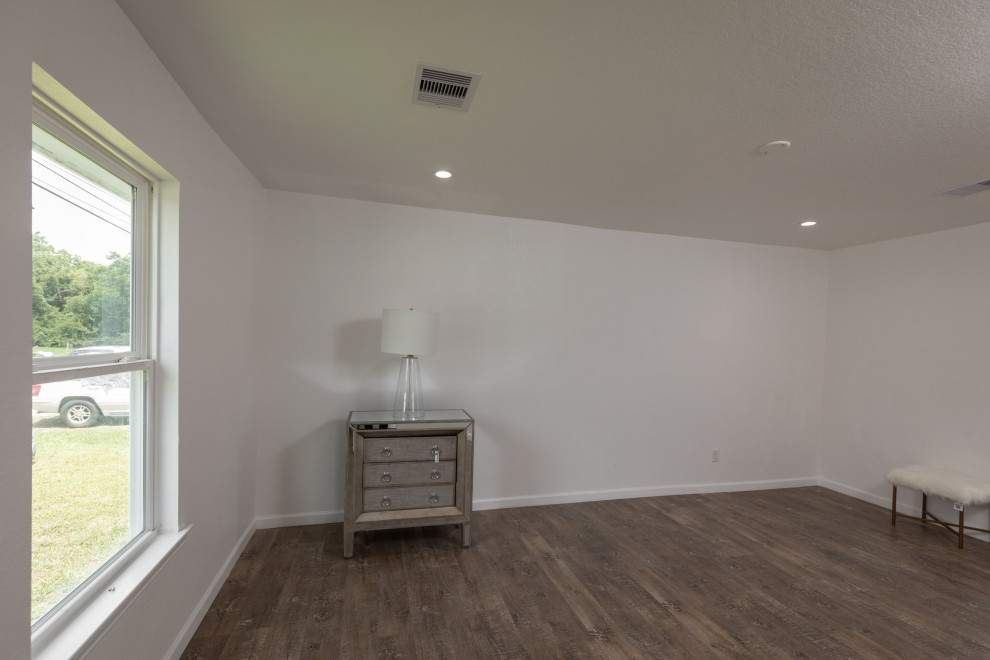 Foto de dormitorio principal campestre de tamaño medio con paredes blancas, suelo laminado y suelo marrón