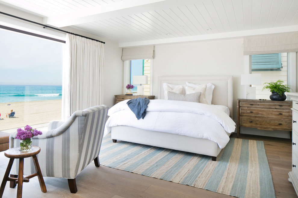 Foto de dormitorio principal costero grande sin chimenea con paredes grises y suelo de madera clara