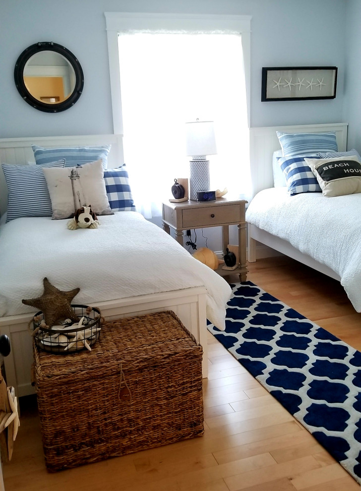 Nautical guest bedroom in Other with grey walls and light hardwood flooring.