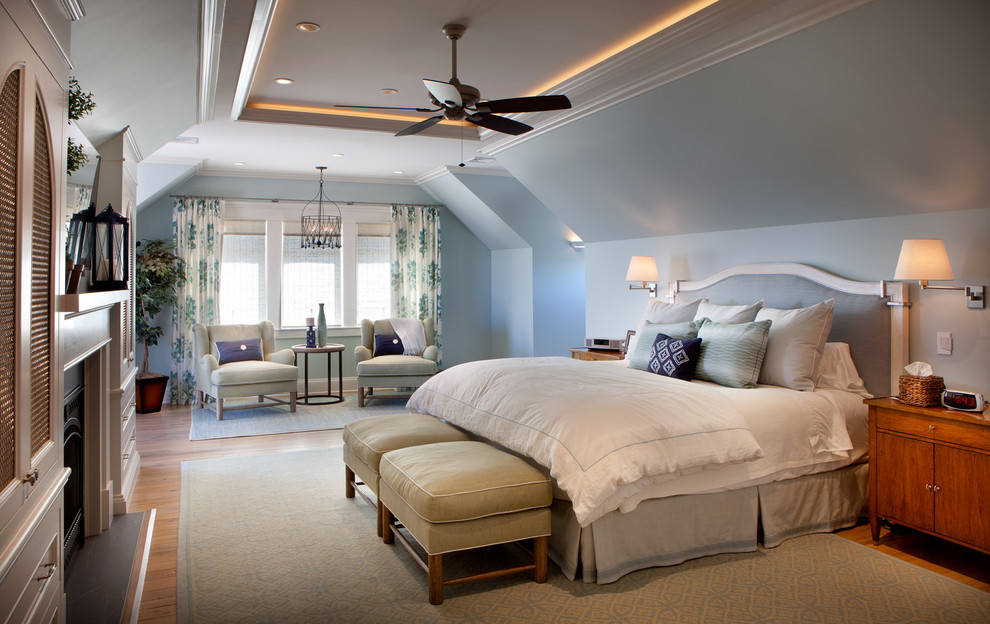Design ideas for a large beach style master bedroom in New York with medium hardwood flooring, brown floors, blue walls, a standard fireplace and a wooden fireplace surround.
