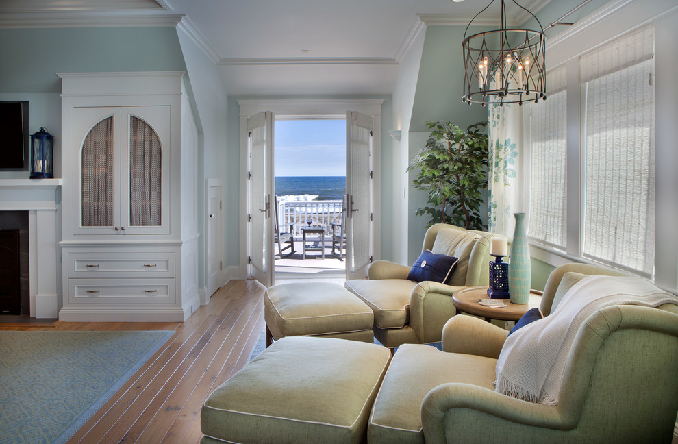 Großes Maritimes Hauptschlafzimmer mit blauer Wandfarbe, braunem Holzboden, Kamin, Kaminumrandung aus Holz und braunem Boden in New York