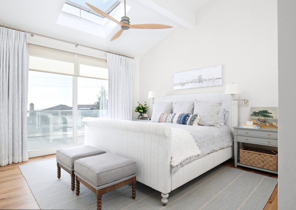 Imagen de dormitorio principal costero de tamaño medio con paredes blancas, suelo de madera en tonos medios y suelo marrón