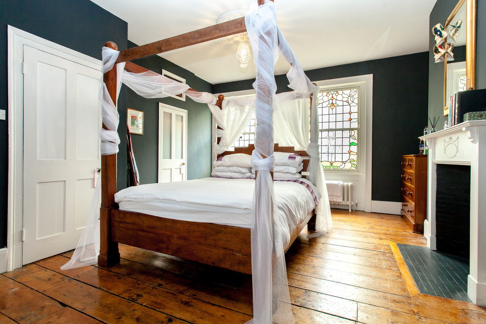 Esempio di una camera da letto eclettica con pareti verdi, pavimento in legno massello medio, camino classico e pavimento marrone