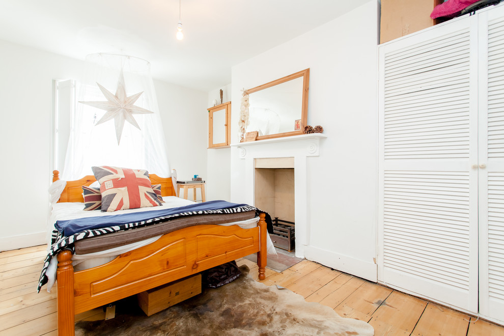 Aménagement d'une chambre éclectique avec un mur blanc, parquet clair, une cheminée standard et un sol beige.