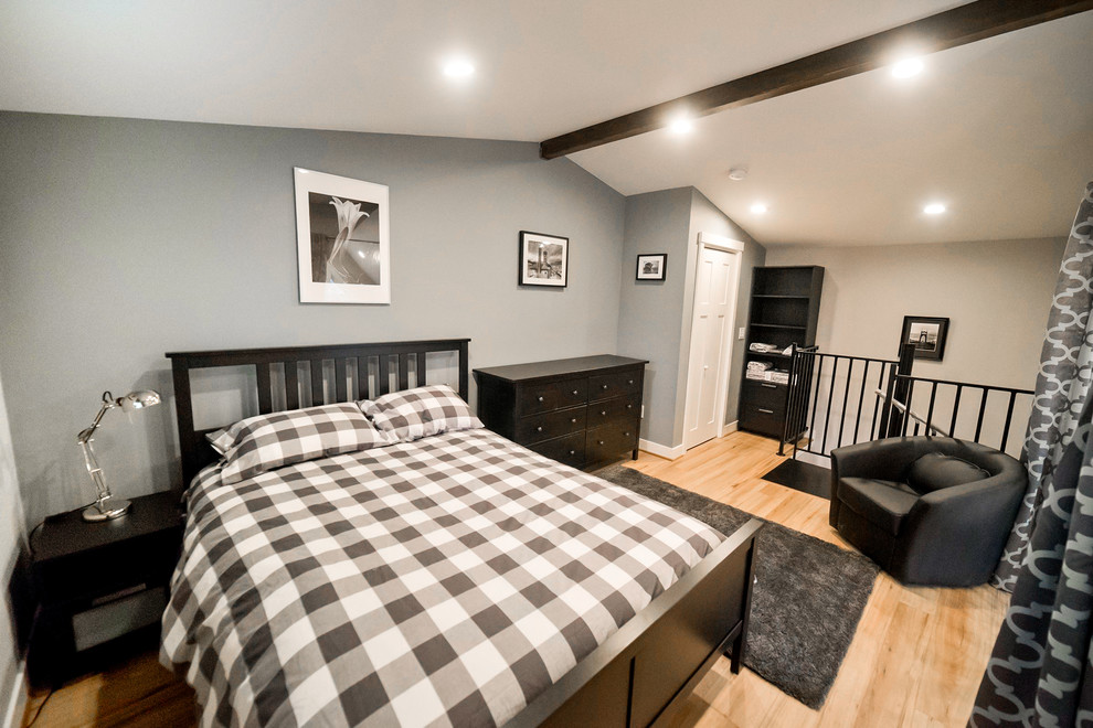Esempio di una piccola camera da letto stile loft chic con pareti grigie e parquet chiaro