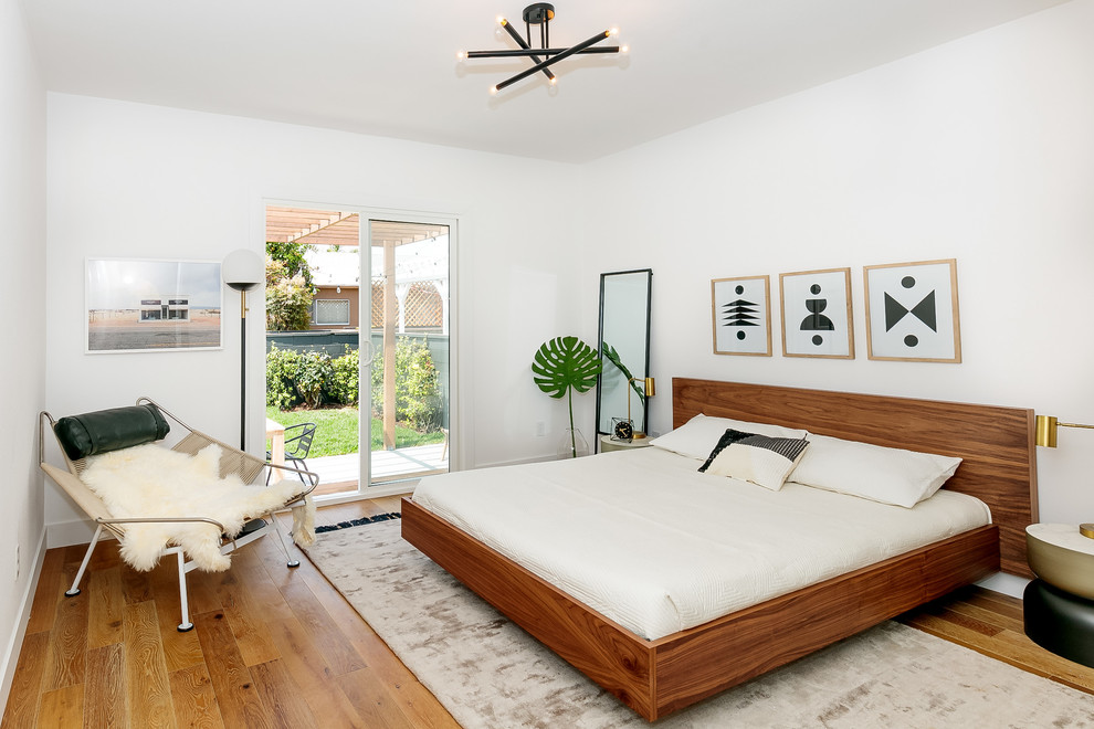 Foto di una camera da letto contemporanea con pareti bianche, pavimento in legno massello medio e pavimento marrone