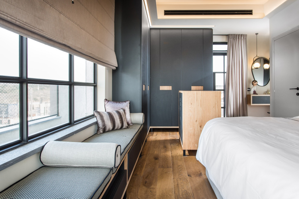 Modelo de dormitorio principal actual de tamaño medio con paredes grises, suelo de madera clara y suelo marrón