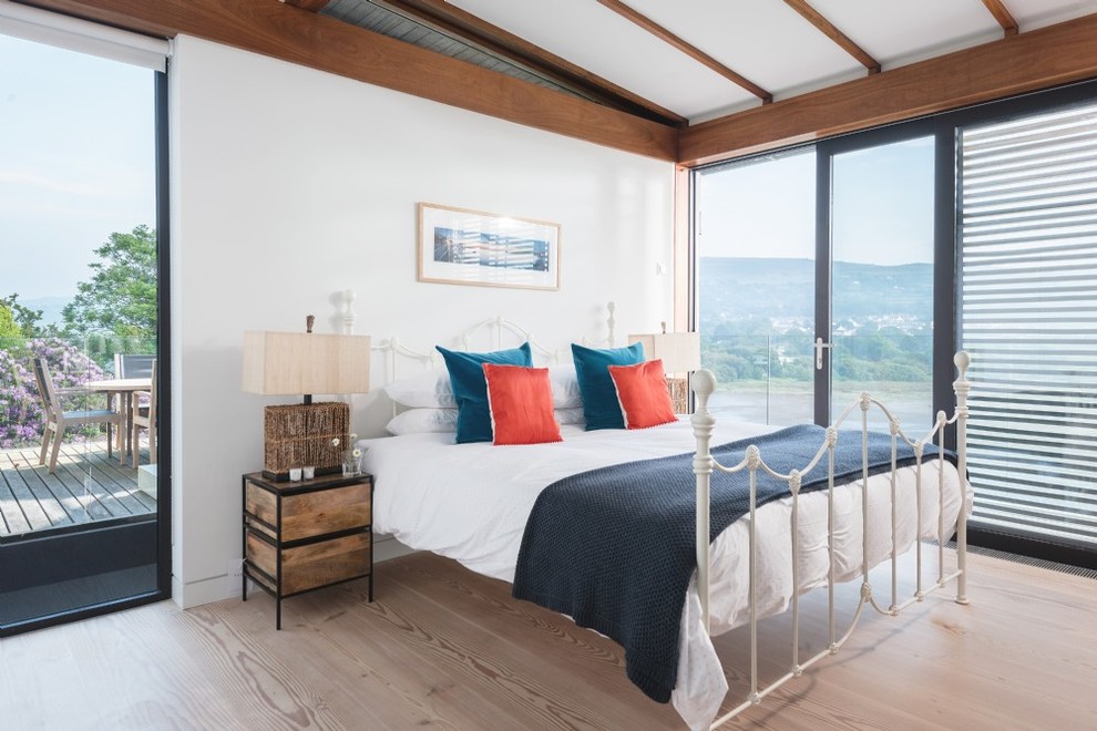 This is an example of a medium sized coastal bedroom in Other with white walls, light hardwood flooring and brown floors.