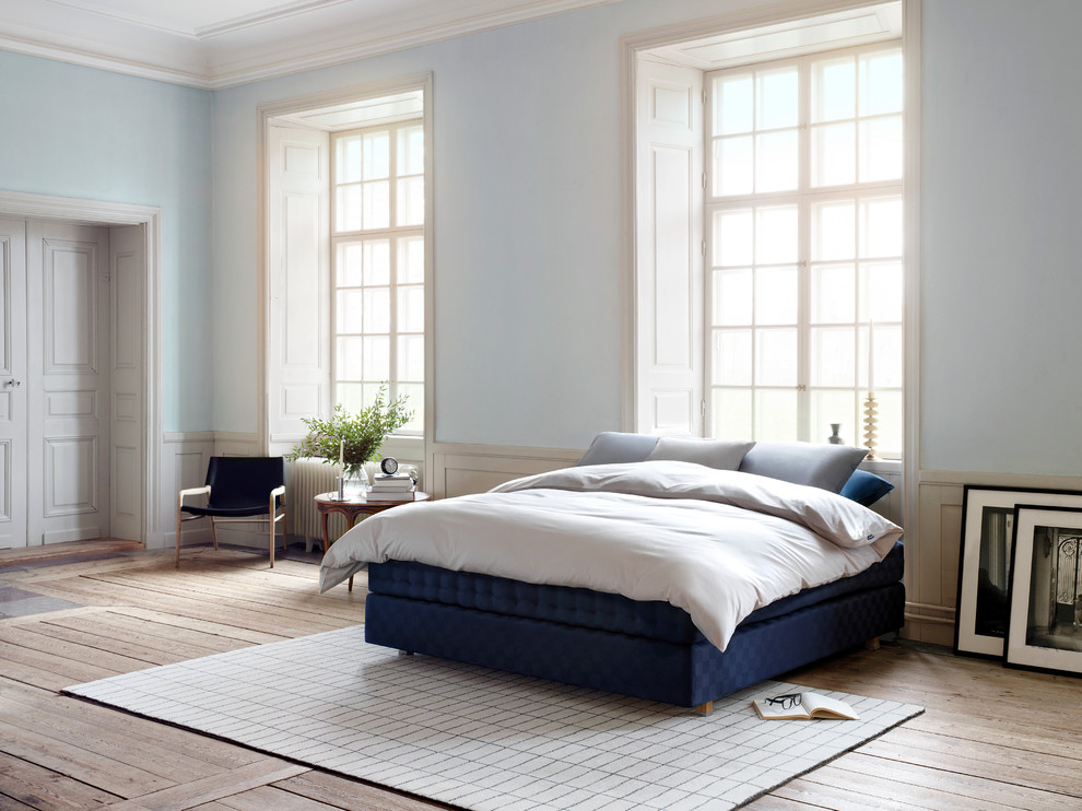Ejemplo de dormitorio principal nórdico grande sin chimenea con paredes azules y suelo de madera en tonos medios