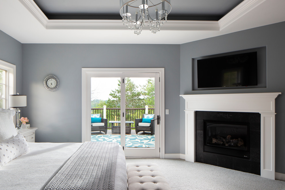 Foto de dormitorio principal de estilo americano grande con paredes grises, moqueta, chimenea de esquina, marco de chimenea de madera y suelo gris
