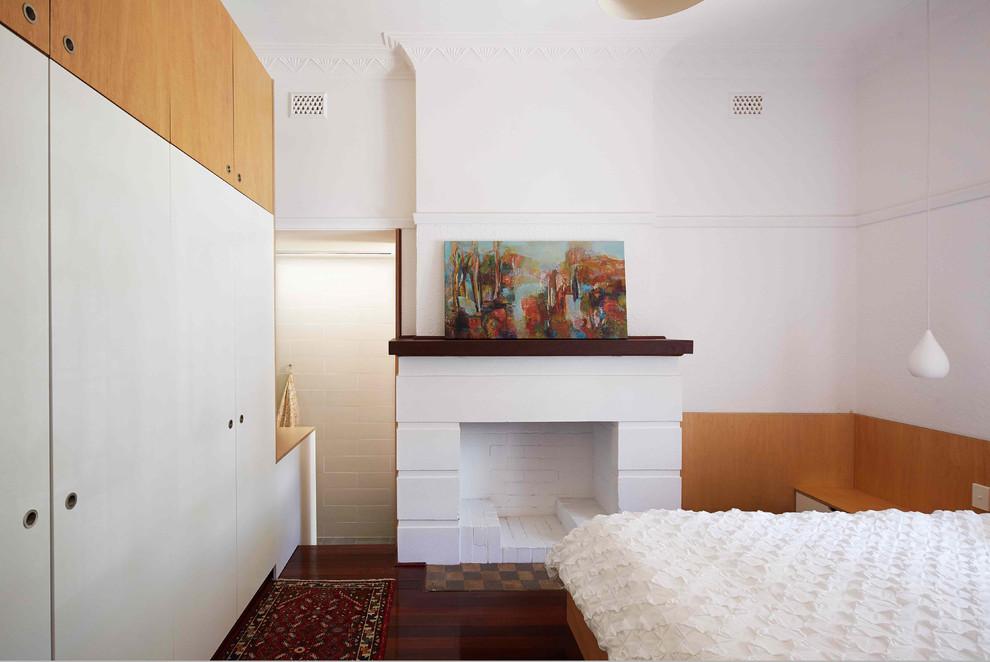Diseño de dormitorio contemporáneo de tamaño medio con paredes blancas, suelo de madera oscura, todas las chimeneas y marco de chimenea de hormigón