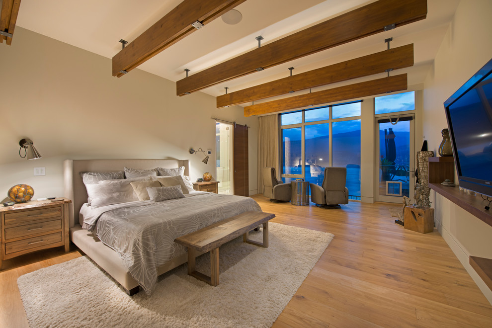 Diseño de dormitorio televisión contemporáneo con paredes beige y suelo de madera en tonos medios