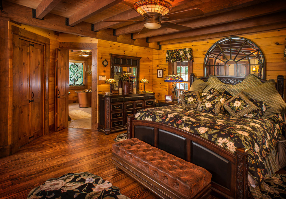 На фото: большая хозяйская спальня в стиле рустика с коричневыми стенами и темным паркетным полом без камина с
