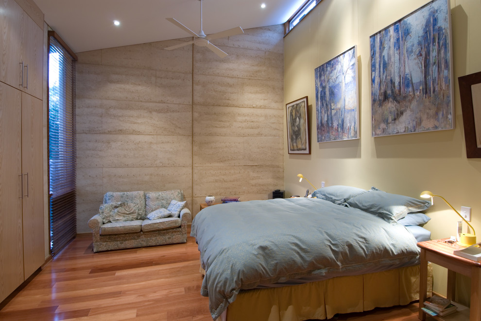Imagen de dormitorio contemporáneo de tamaño medio sin chimenea con paredes amarillas y suelo de madera en tonos medios