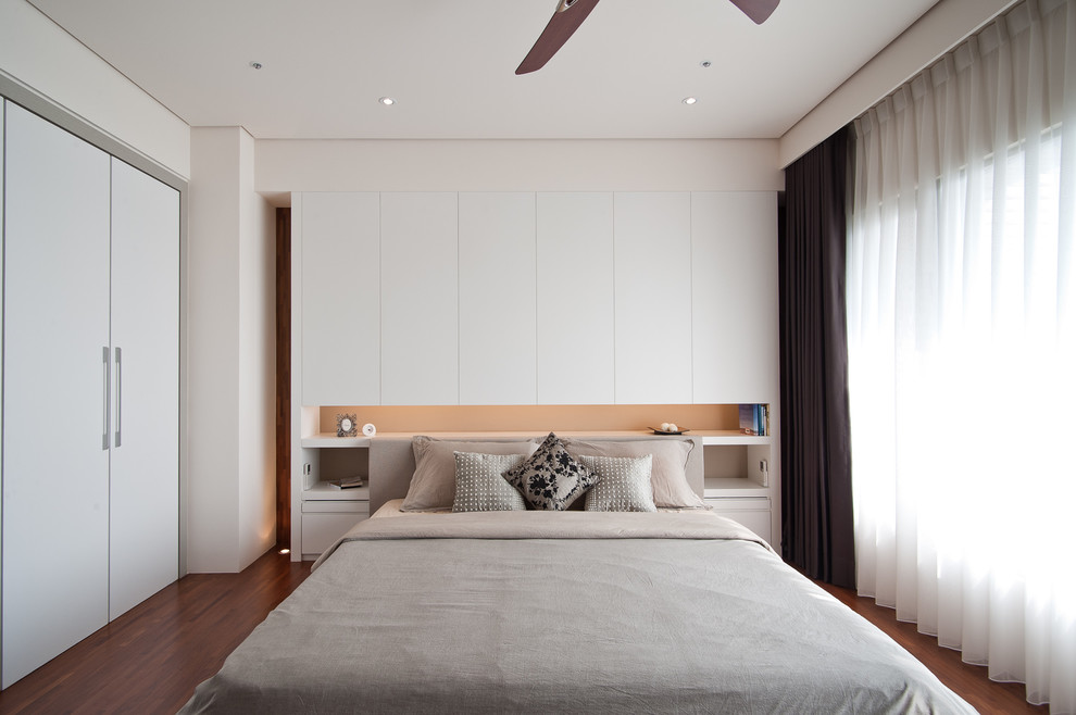 This is an example of a contemporary bedroom in Other with white walls, medium hardwood flooring and no fireplace.