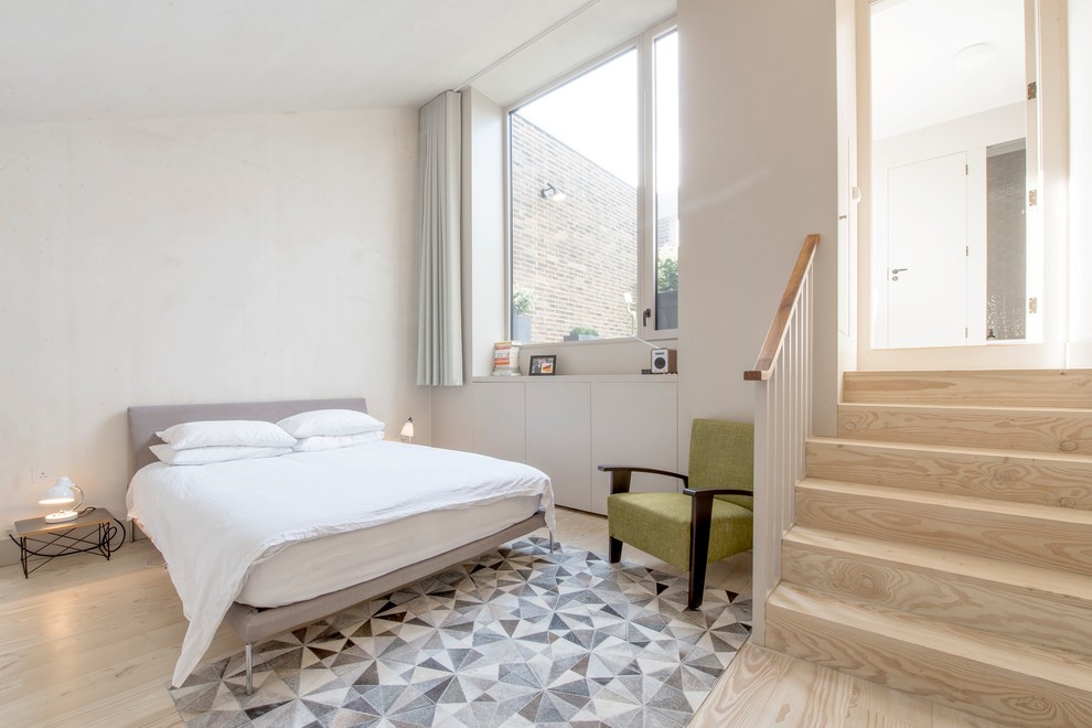 Foto de habitación de invitados nórdica con paredes blancas, suelo de madera clara y suelo beige
