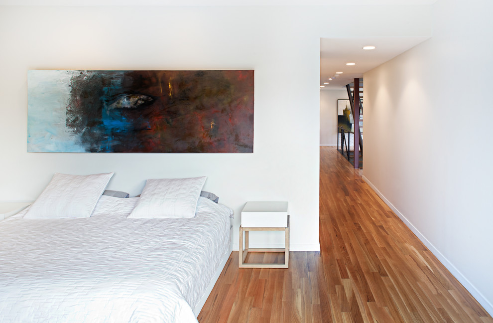 Imagen de dormitorio moderno con paredes blancas y suelo de madera en tonos medios
