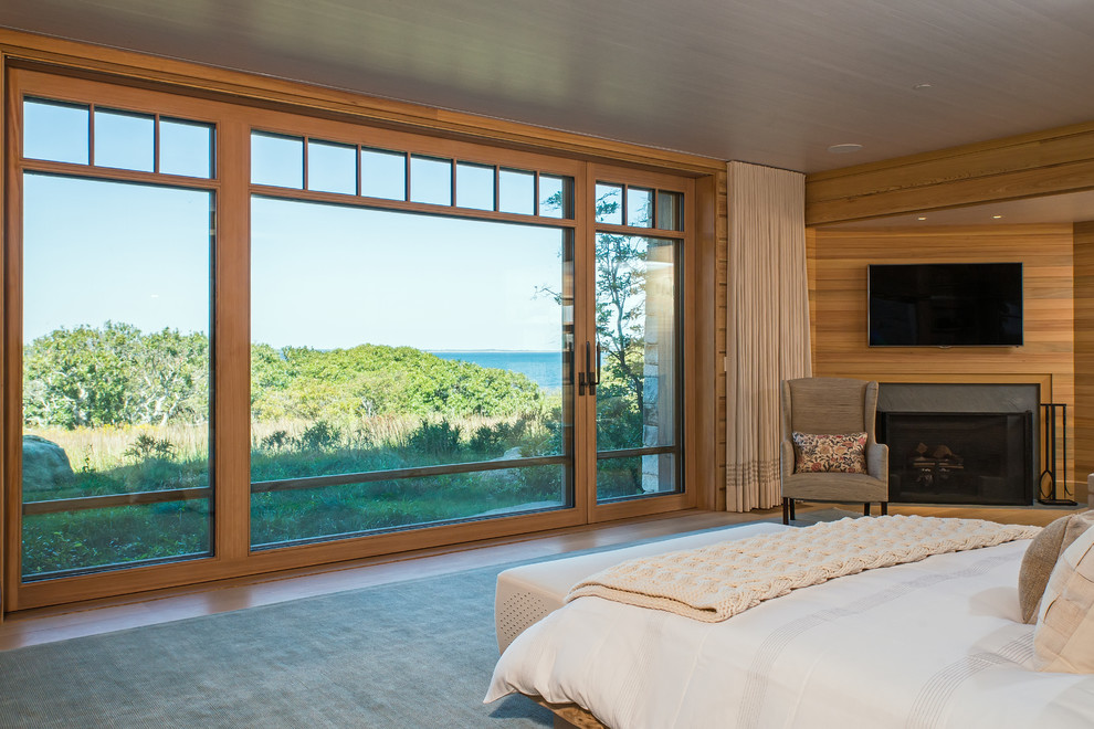 Aménagement d'une chambre d'amis bord de mer de taille moyenne avec un mur beige, un sol en bois brun, une cheminée d'angle et un manteau de cheminée en bois.
