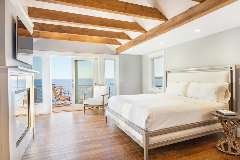 На фото: большая хозяйская спальня в морском стиле с серыми стенами, паркетным полом среднего тона, стандартным камином и фасадом камина из плитки