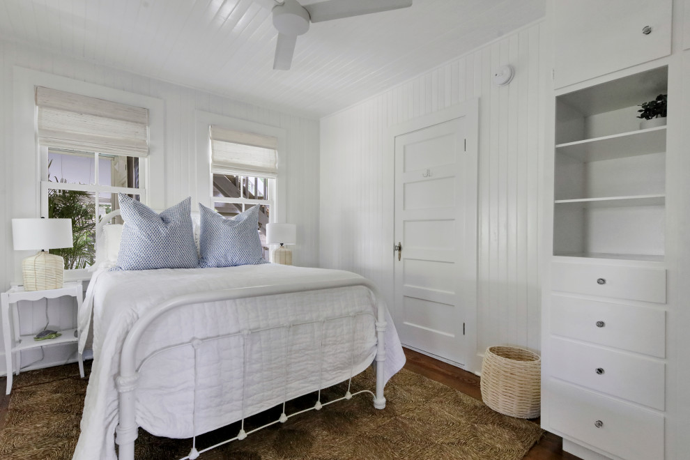 Modelo de dormitorio costero con paredes blancas, suelo de madera en tonos medios, suelo marrón, madera y madera