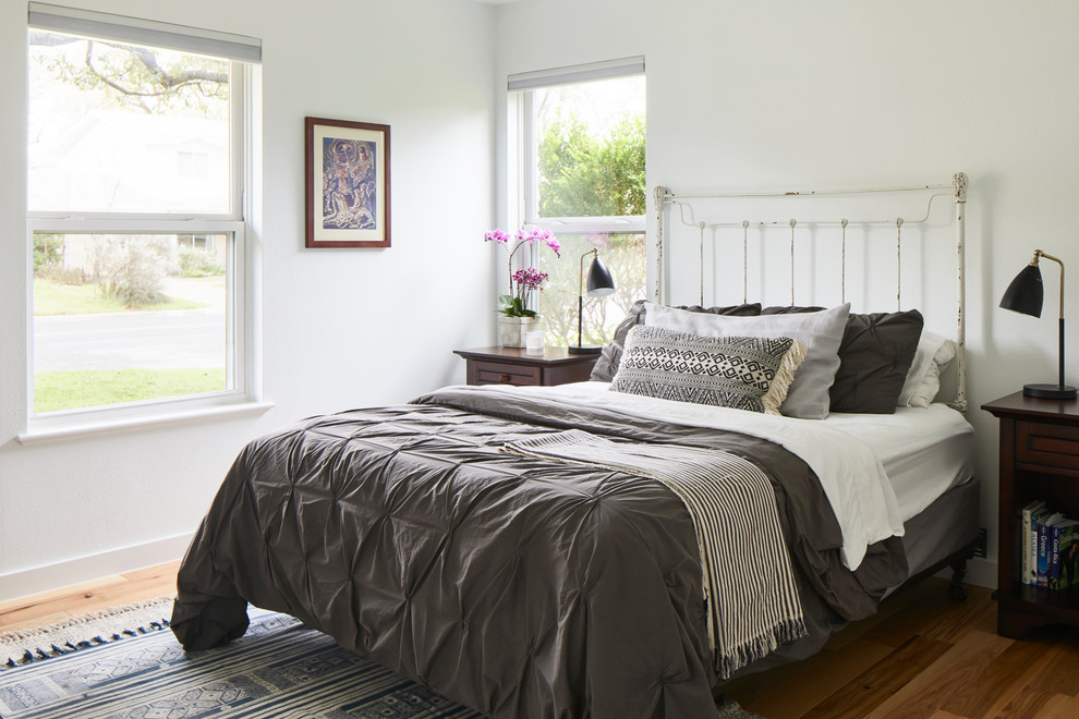 オースティンにある中くらいなトランジショナルスタイルのおしゃれな客用寝室 (白い壁、暖炉なし、茶色い床、無垢フローリング)