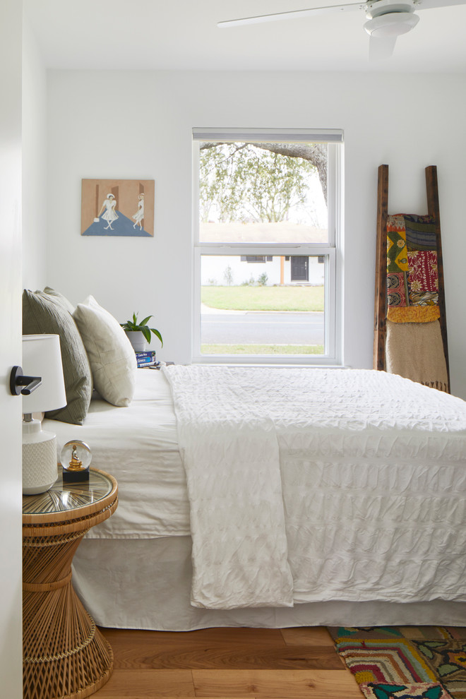 オースティンにある中くらいなエクレクティックスタイルのおしゃれな客用寝室 (白い壁、淡色無垢フローリング、暖炉なし、茶色い床)