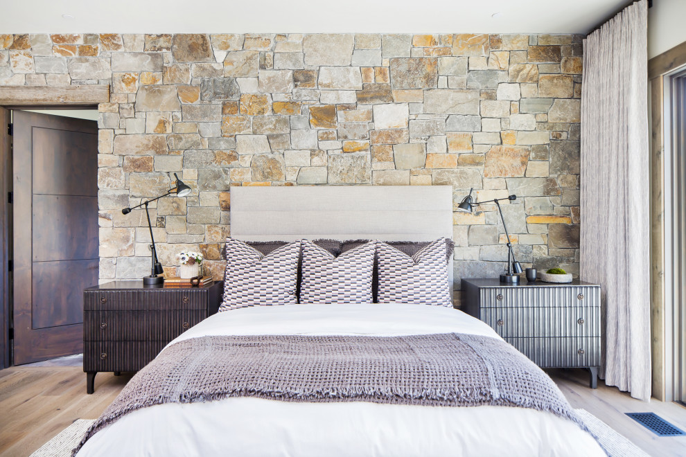 Großes Rustikales Hauptschlafzimmer mit Kamin, Kaminumrandung aus Stein, brauner Wandfarbe, hellem Holzboden und beigem Boden