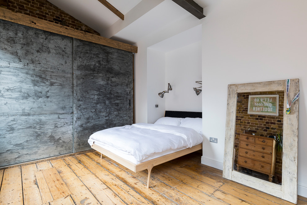Immagine di una camera matrimoniale industriale di medie dimensioni con pavimento in legno massello medio
