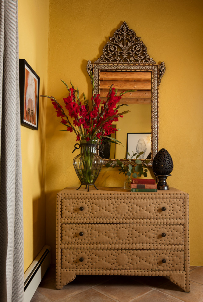 Mittelgroßes Eklektisches Hauptschlafzimmer mit gelber Wandfarbe, Porzellan-Bodenfliesen, Eckkamin und verputzter Kaminumrandung in Albuquerque