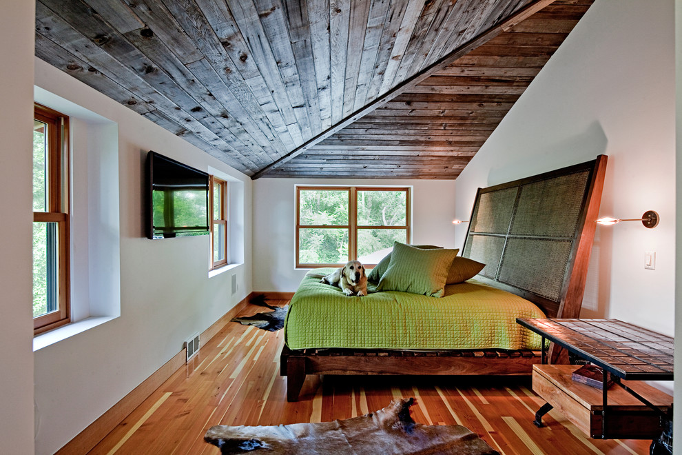 Cette photo montre une chambre tendance avec un mur blanc et un sol en bois brun.