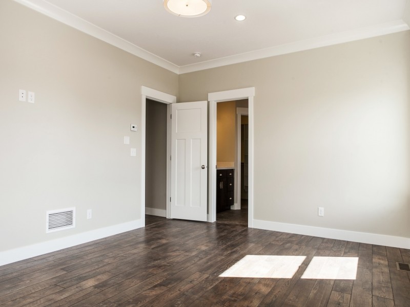 Exemple d'une grande chambre parentale craftsman avec un mur beige et un sol en bois brun.
