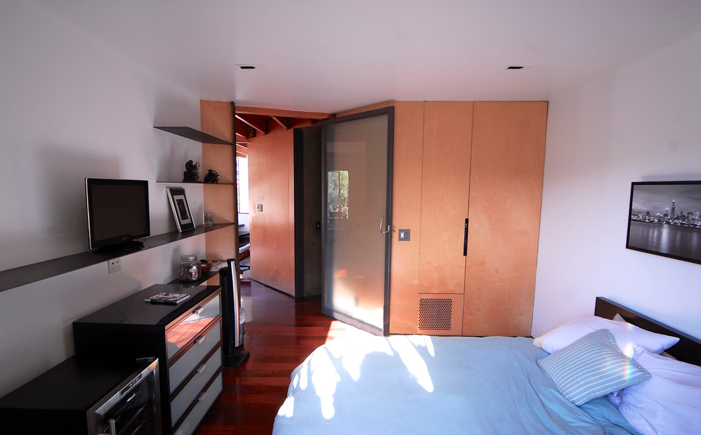 Exemple d'une chambre d'amis chic de taille moyenne avec parquet foncé et un mur blanc.