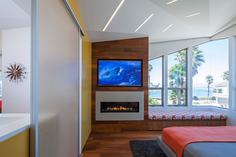 Photo of a medium sized contemporary guest bedroom in Los Angeles with white walls, medium hardwood flooring, a ribbon fireplace, a metal fireplace surround and brown floors.
