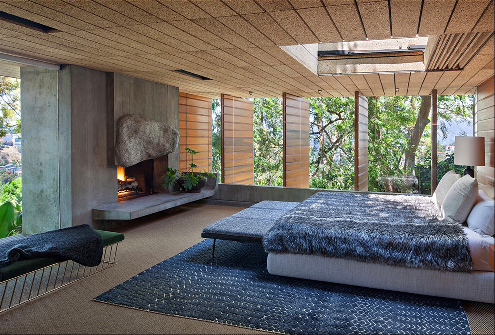 This is an example of a midcentury master bedroom in Los Angeles with carpet, a concrete fireplace surround and grey floors.