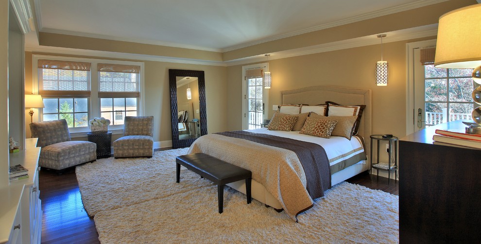 Modelo de dormitorio principal actual grande con paredes beige y suelo de madera oscura