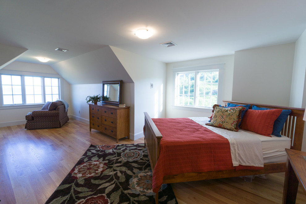 Modelo de dormitorio clásico grande con paredes blancas, suelo de madera clara y suelo beige
