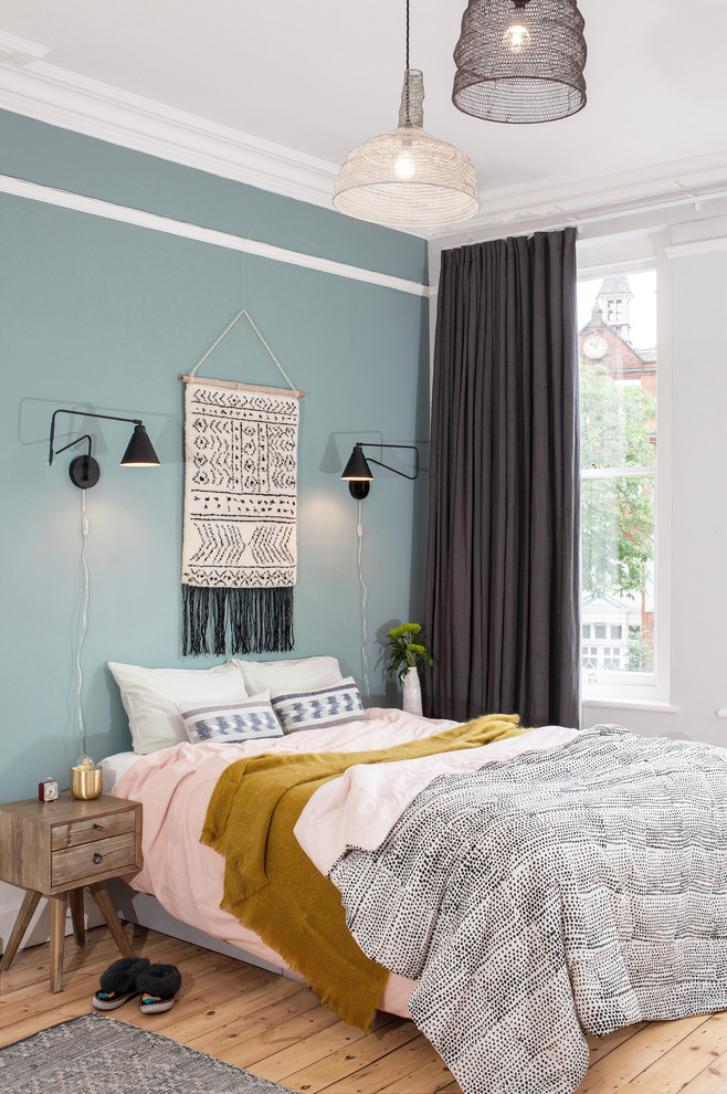 Example of a mid-sized danish light wood floor and beige floor bedroom design in London with blue walls
