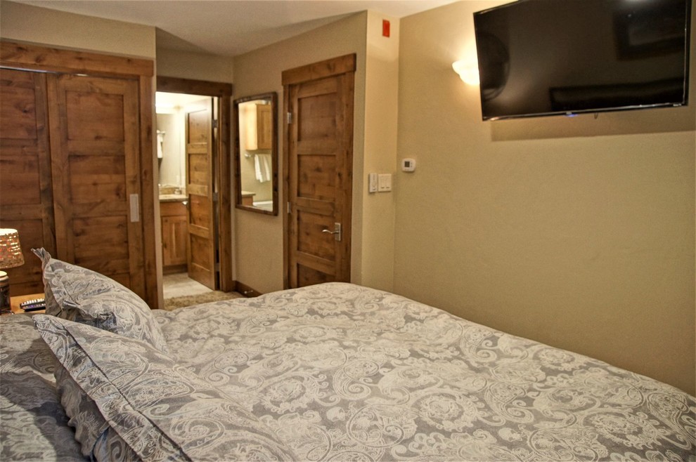 Modelo de dormitorio principal rústico de tamaño medio con paredes beige, moqueta y suelo beige